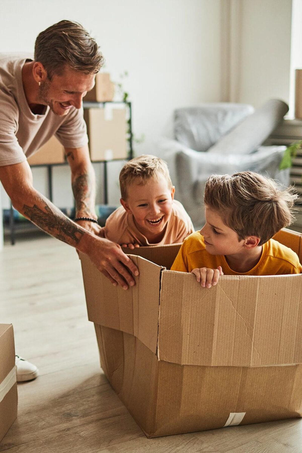 father playing with two boys in cardboard box while family moving to new house